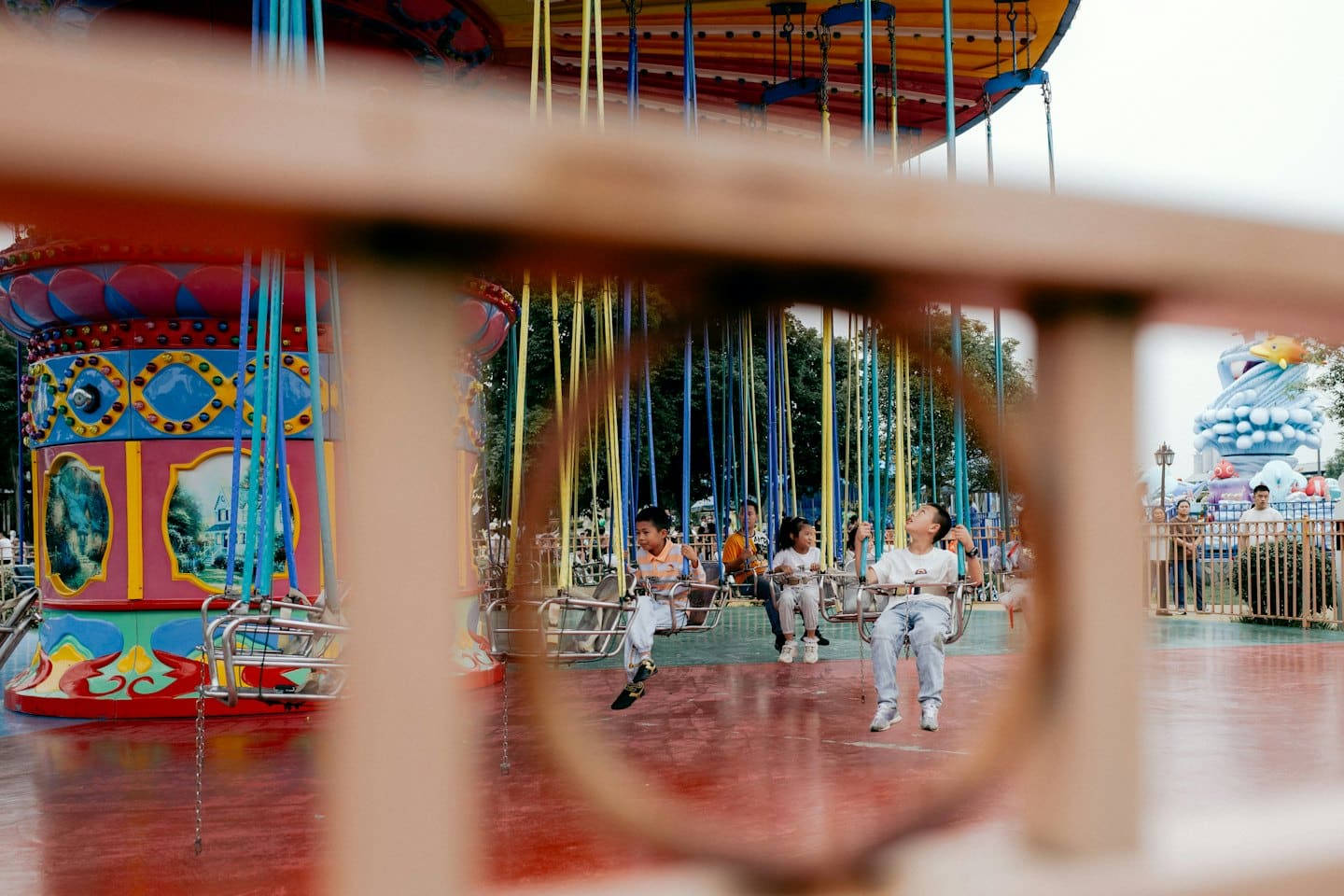 Trois enfants sur un manège coloré dans une fête foraine.