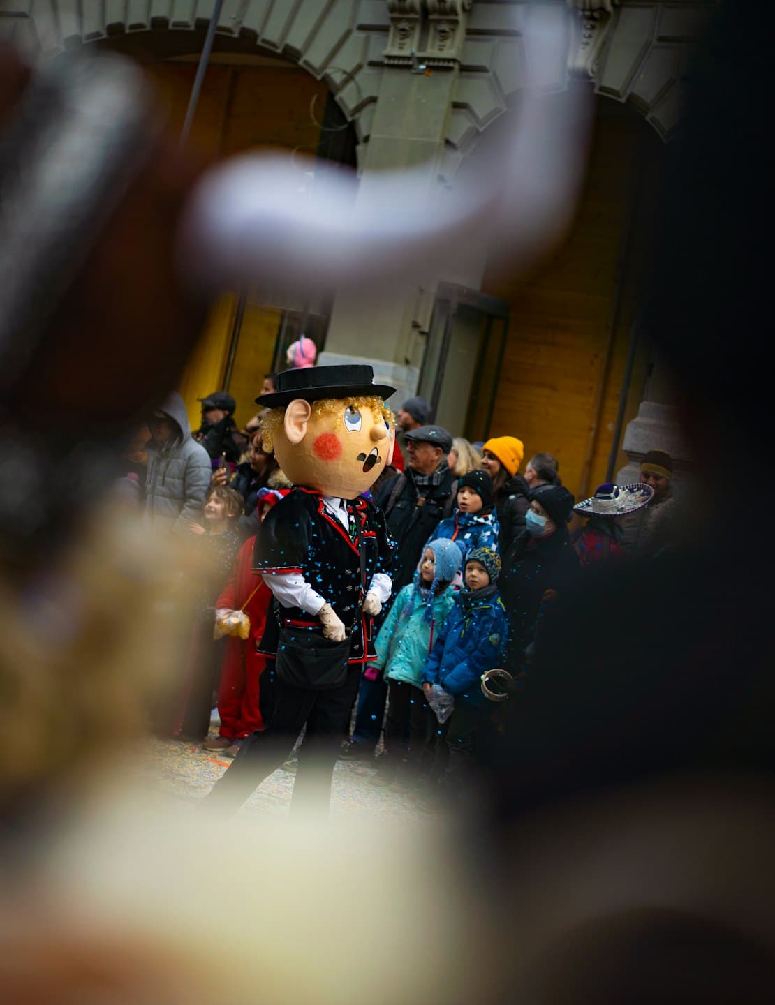 Un homme en costume de mascotte se tient parmi les participants à un festival.