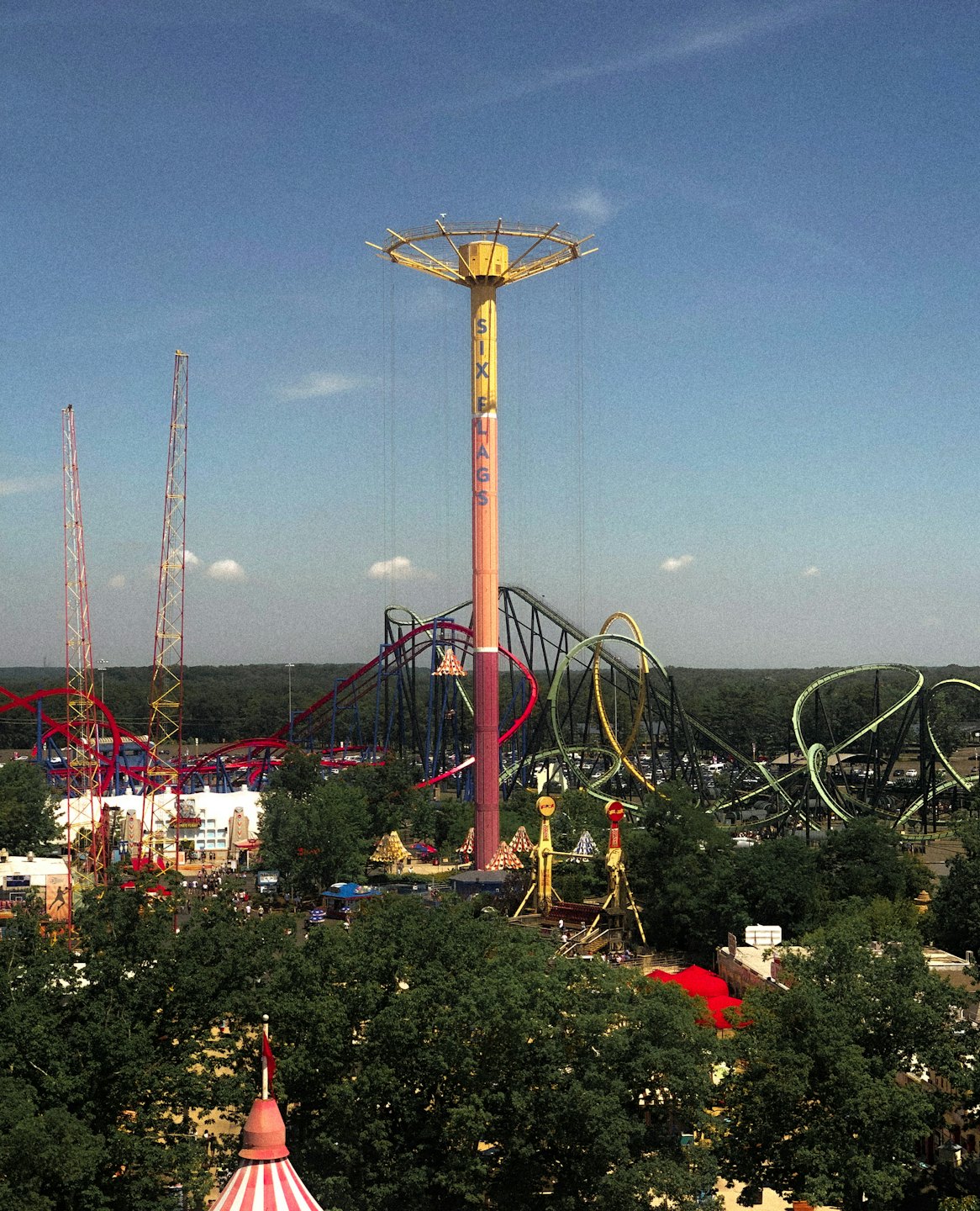 Un parc d'attractions avec des montagnes russes colorées et une tour de chute.