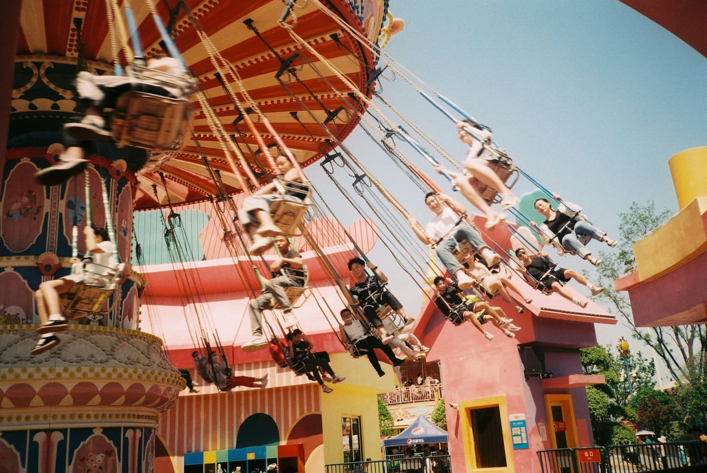 Des gens s'amusent sur un manège à chevaux coloré dans un parc d'attractions.